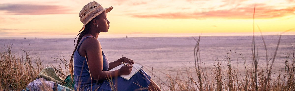 woman journaling at sunset by water